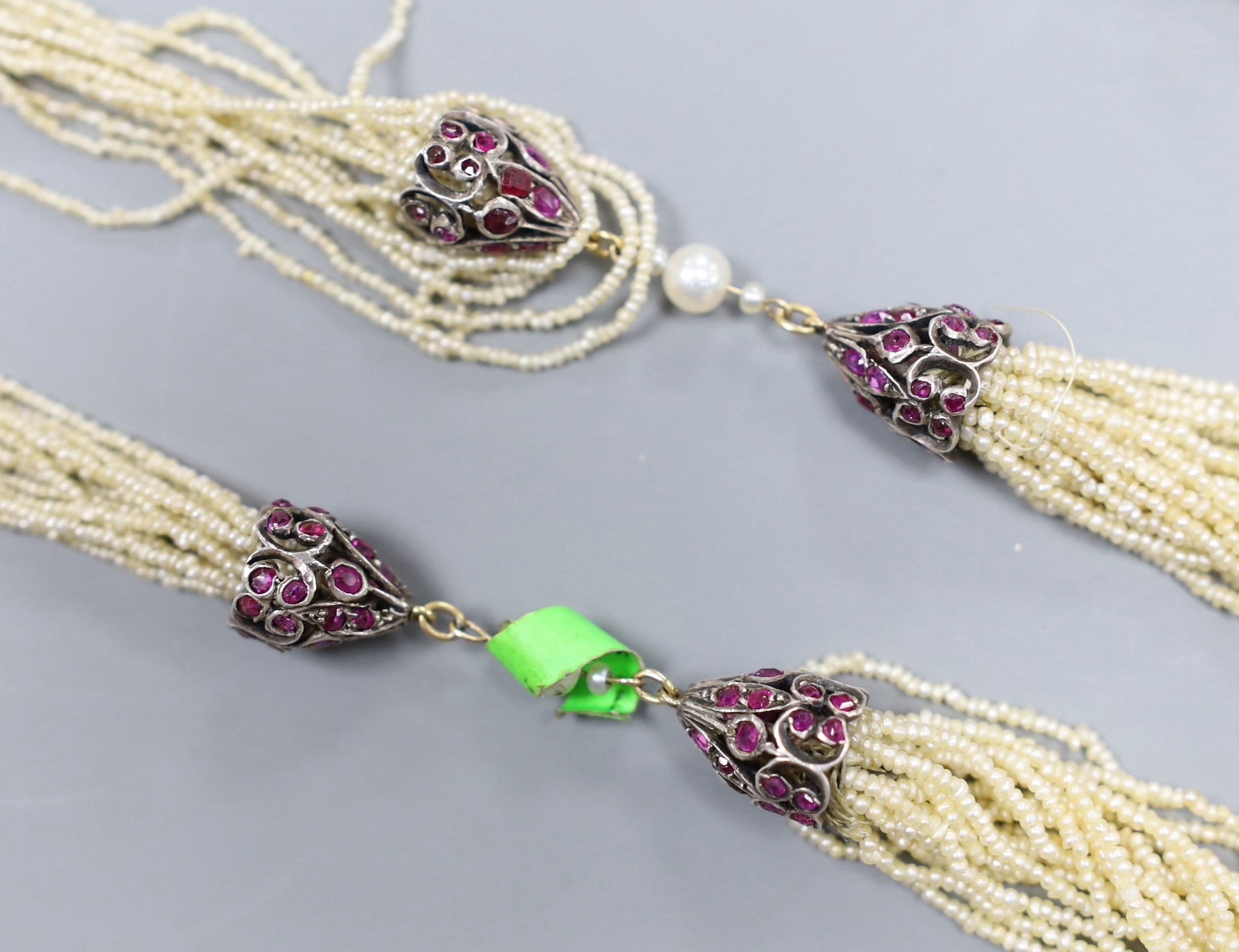 An Indian multi-strand seed pearl sautoir necklace, with ruby set white metal terminals, length 130cm